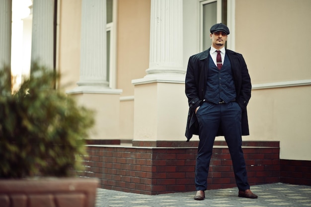 Free photo portrait of retro 1920s english arabian business man wearing dark coat suit tie and flat cap