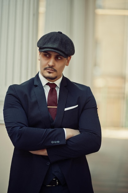 Portrait of retro 1920s english arabian business man wearing dark suit tie and flat cap