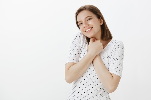 Portrait of romantic and tender cute woman press hands to chest and smiling adorable