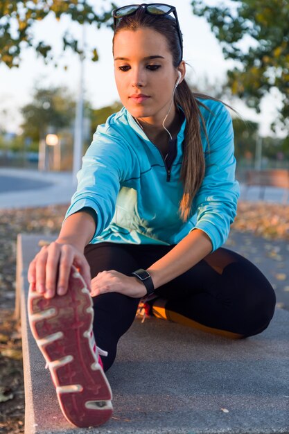 Portrait of running woman doing stretching in the park.