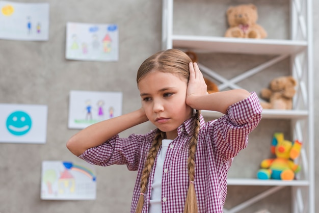 Free photo portrait of sad girl covering her ears with two hands