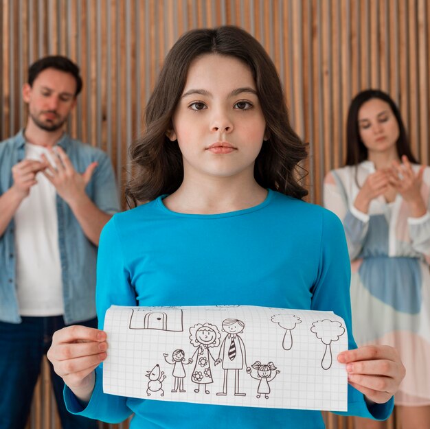 portrait of sad girl holding family drawing