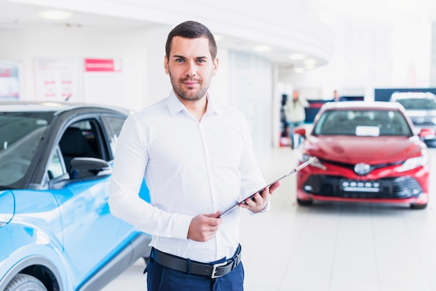 Free photo portrait of salesman in car dealership