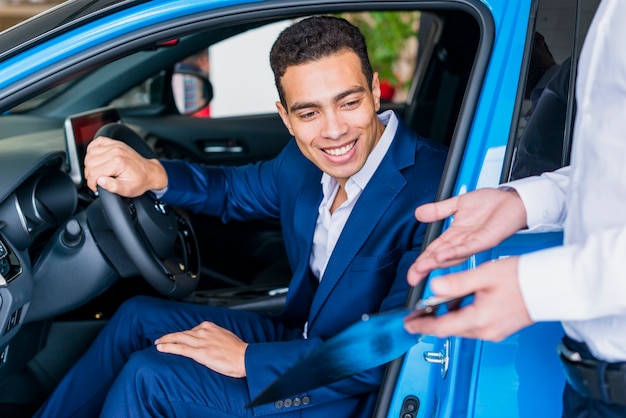 Free photo portrait of salesman in car dealership