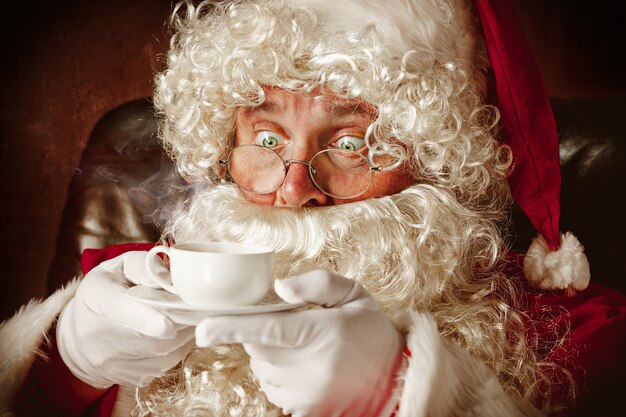 Portrait of Santa Claus in red costume with coffee cup