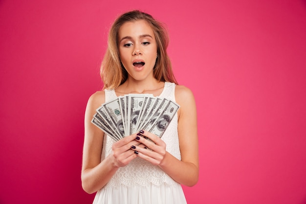 Free photo portrait of a satisfied pretty girl counting money banknotes