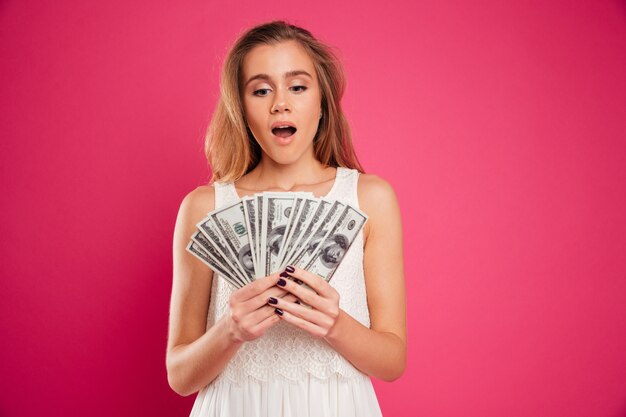 Portrait of a satisfied pretty girl counting money banknotes