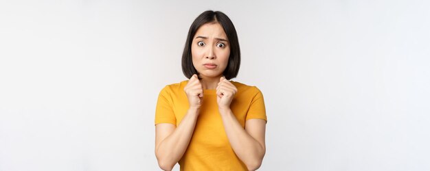 Portrait of scared asian woman shaking from fear looking terrified and concerned standing anxious against white background