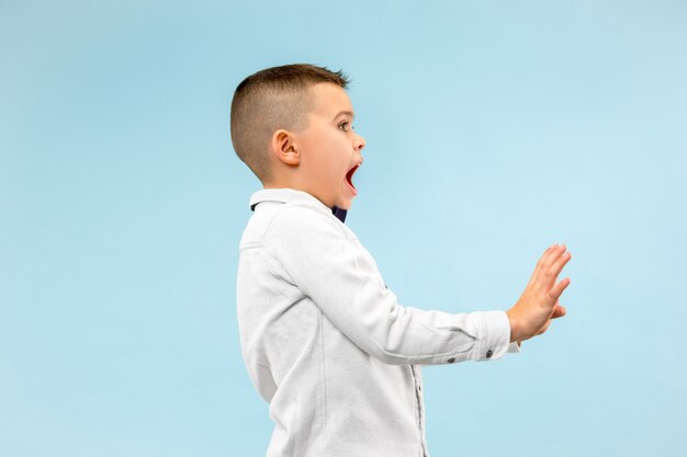 Portrait of the scared boy. Teenager standing isolated on trendy blue studio background. male half-length portrait.