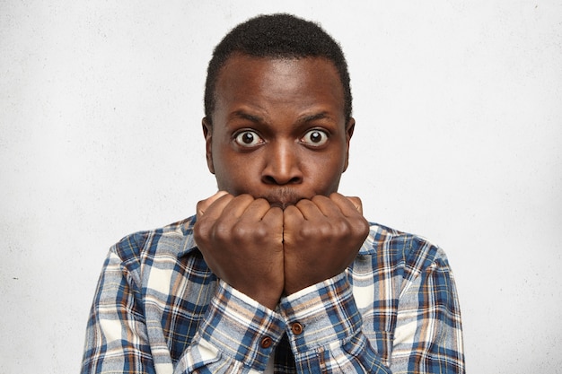 Free photo portrait of scared young african american man dressed in stylish checkered shirt