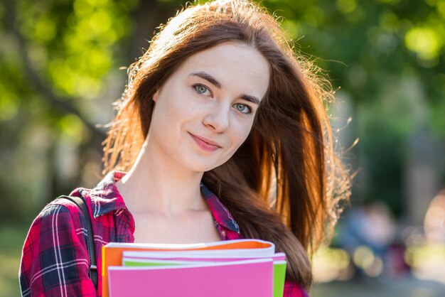 Portrait of school girl with books in park
