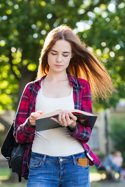 Portrait of school girl with books in park