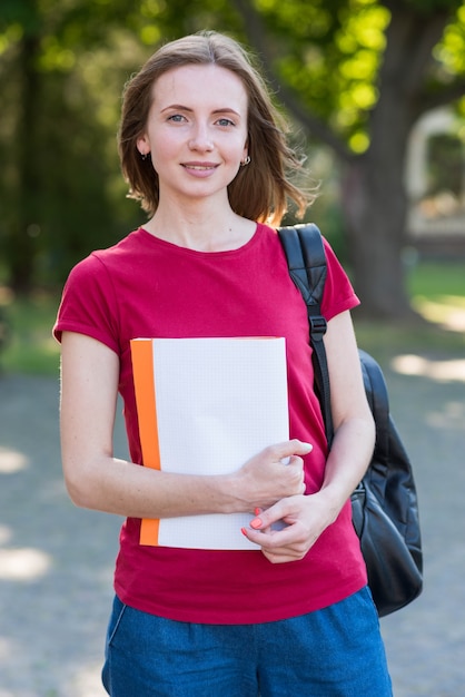 Portrait of school girl with books in park