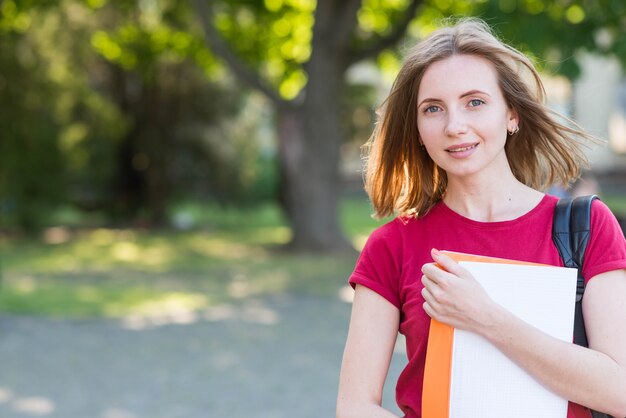 Portrait of school girl with books in park