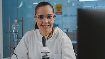 Portrait of scientist analyzing liquid sample on microscope tray in laboratory to research dna genetic. lab worker with safety glasses using optical glass tool for scientific development.