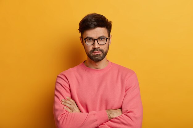 Portrait of self confident serious male entrepreneur keeps hands crossed