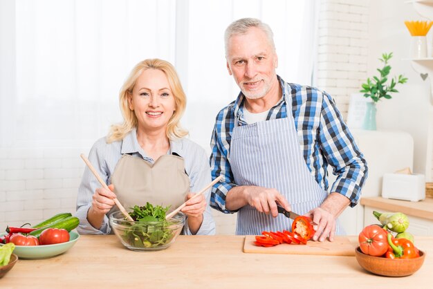 Portrait of a senior couple preparing the food in the kitchen
