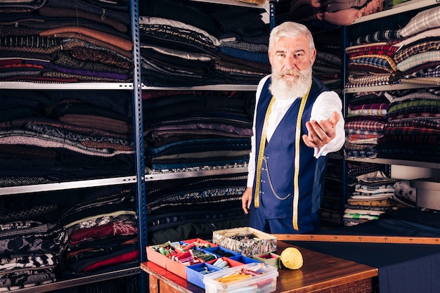 Free photo portrait of a senior male fashion designer inviting someone in his shop