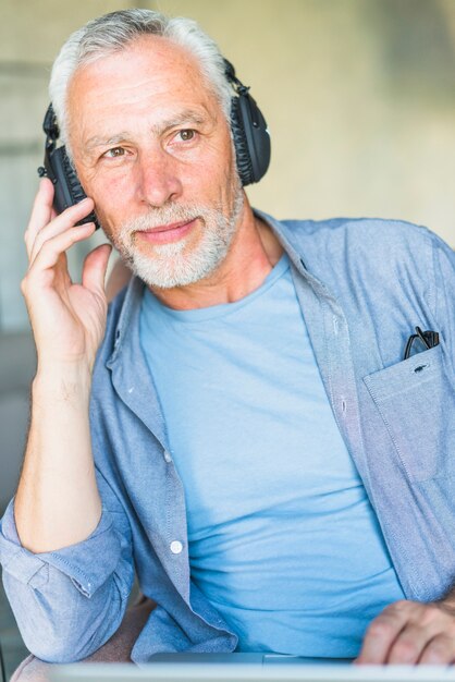 Portrait of senior male listening music on headphone