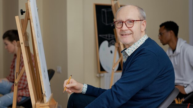 Portrait of senior man attending drawing workshop in studio to develop creative new skills. Art class lesson to draw inspiration model as leisure activity for educational and artistic growth.