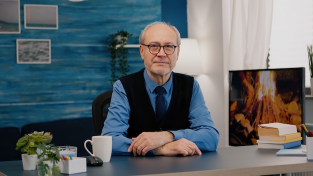 Portrait of senior man chatting and listening remote teamwork during video call working from home. An elderly person using internet online chat technology webcam making virtual meeting call connection