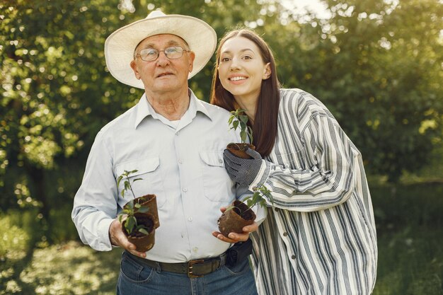 Portrait of senior man in a hat gardening with granddaugher