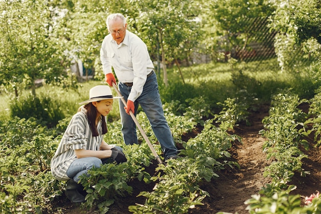 Portrait of senior man in a hat gardening with granddaugher