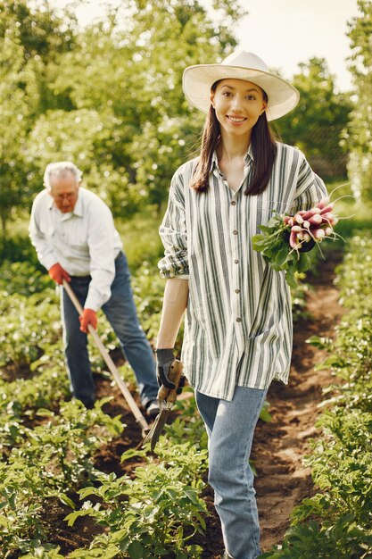 Portrait of senior man in a hat gardening with granddaugher