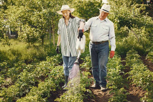 Portrait of senior man in a hat gardening with granddaugher