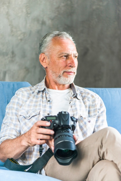 Free photo portrait of senior man holding dslr camera