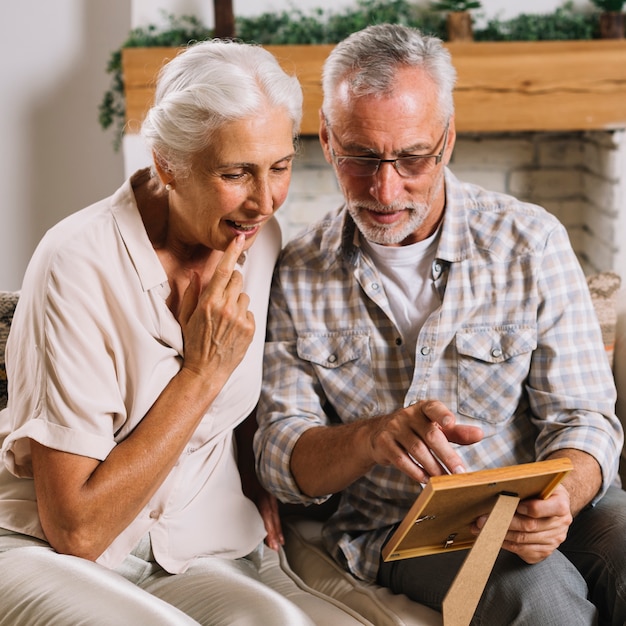 Portrait of senior man showing photo frame to her wife