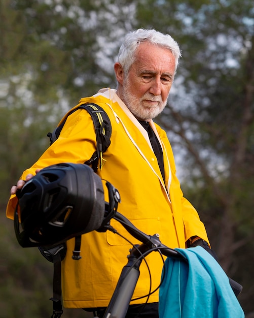 Free photo portrait senior man with bike on mountain