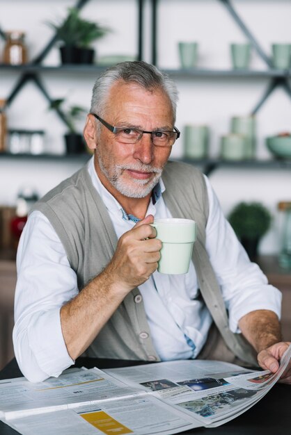 新聞を読んで彼の手でコーヒーカップで上司の肖像画の肖像