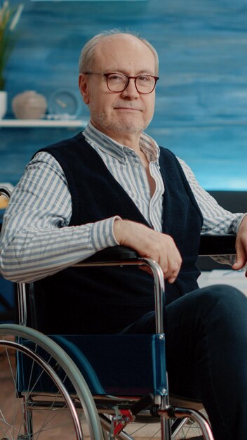 portrait of senior man with disability living in nursing home. elder disabled person in wheelchair and looking at camera, needing support and assistance from caregiver as facility resident.