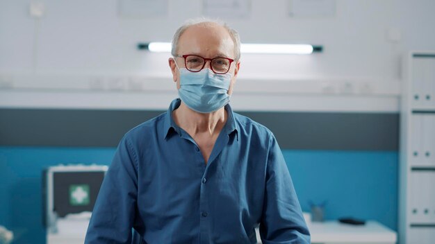 Portrait of senior patient attending medical consultation in cabinet, during coronavirus pandemic. Elder person looking at camera and waiting on medic to discuss about health care treatment.