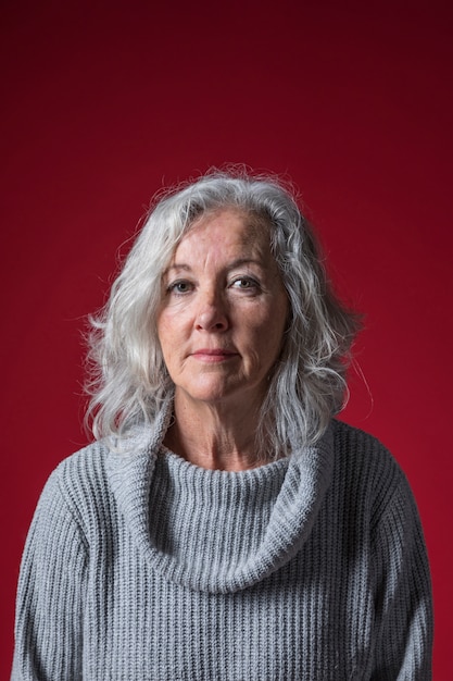 Portrait of a senior woman against red backdrop