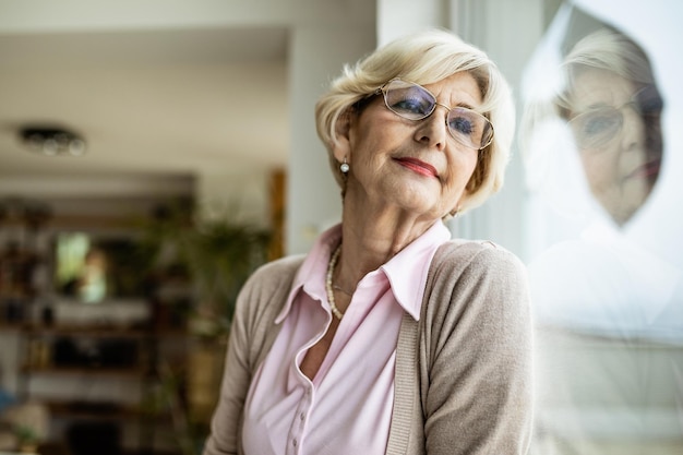 Portrait of senior woman day dreaming by the window and looking through it