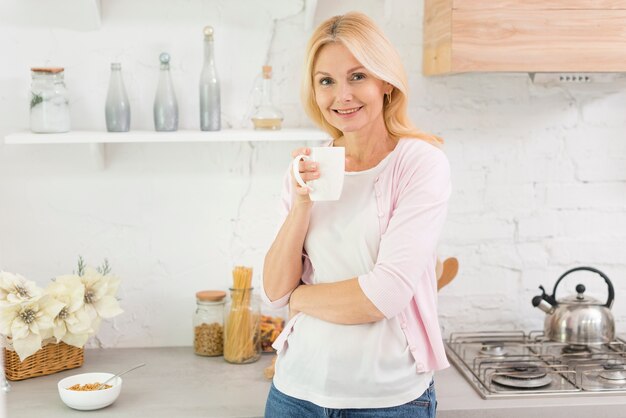 コーヒーのカップを保持している年配の女性の肖像画