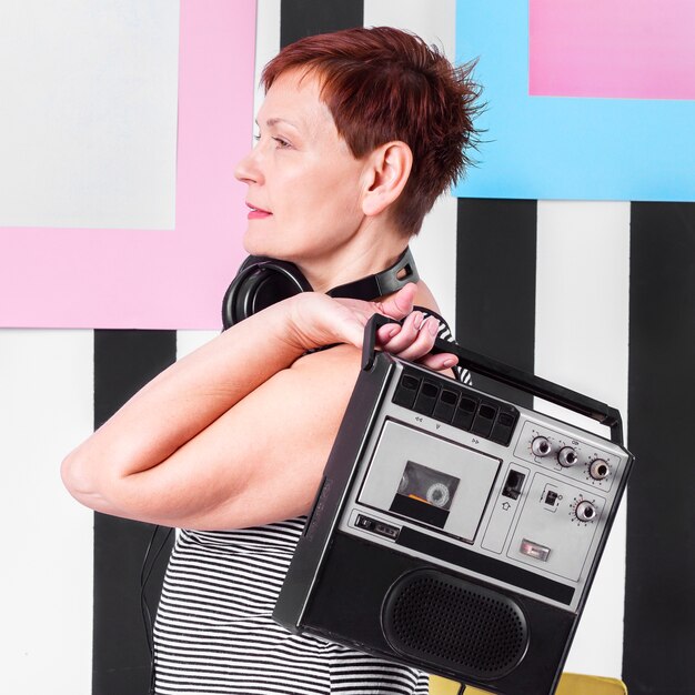 Portrait of a senior woman holding a vintage cassette player