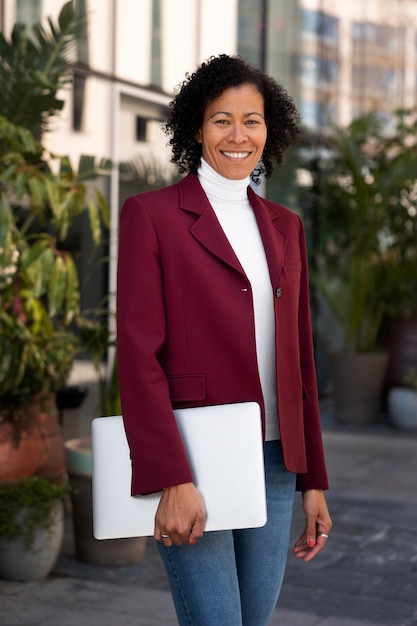 Portrait of senior woman in professional blazer outdoors and laptop