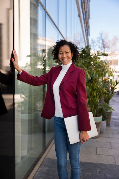 Portrait of senior woman in professional blazer outdoors and laptop