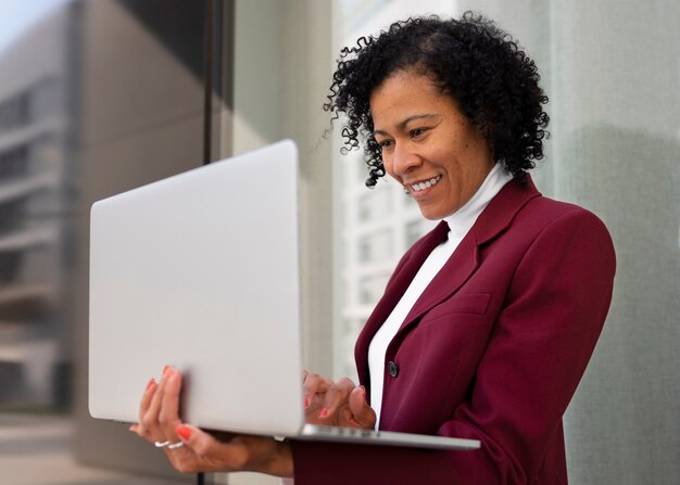 Portrait of senior woman in professional blazer outdoors and laptop