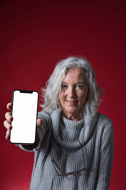 Foto gratuita ritratto di una donna senior che mostra telefono cellulare con display bianco bianco