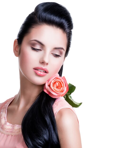 Portrait of sensual beautiful woman with pink rose on white wall.