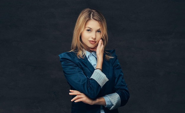 Portrait of a sensual blonde business woman dressed in a formal suit and blue shirt. Isolated on a dark background.