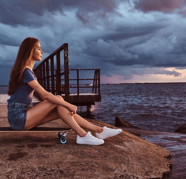 Premium Photo Portrait Of A Sensual Girl Sitting On A Skateboard On The Beach Is Enjoying