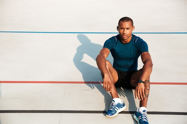 Портрет серьезного африканского человека фитнеса в отдыхать наушников