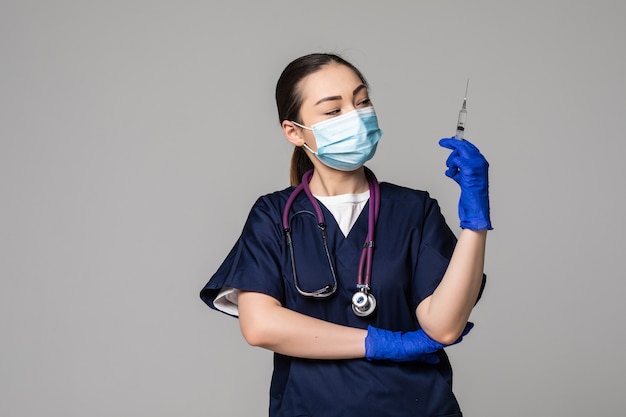 Портрет серьезной азиатской молодой женщины-медсестры в медицинской маске, держащей шприц с вакциной от вируса