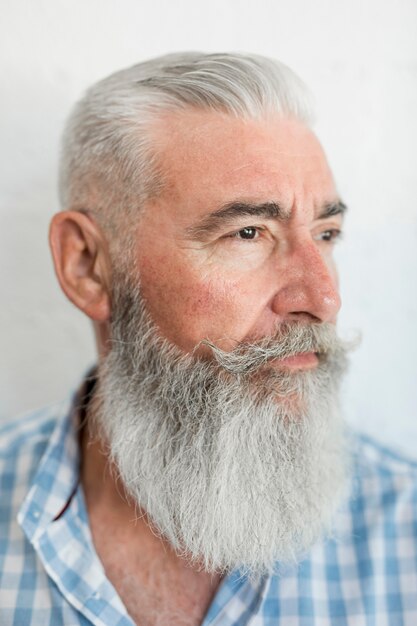 Портрет серьезного бородатого старца в рубашке в студии