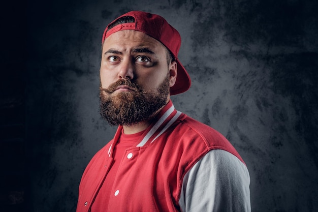 Foto gratuita ritratto di uomo serio e barbuto in abiti hip hop su sfondo grigio.